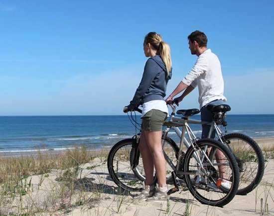 A man and a woman stand with bicycles on a sandy beach in Port St. Joe, Florida, overlooking the ocean.