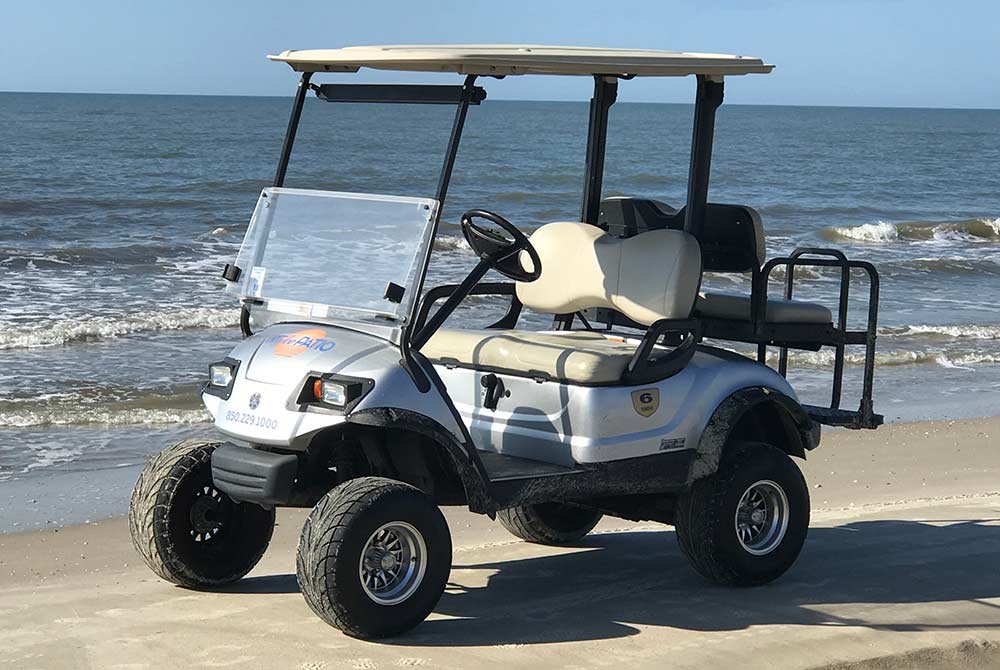 Silver golf cart parked on a sandy beach in Port St. Joe, Florida, with the ocean in the background.