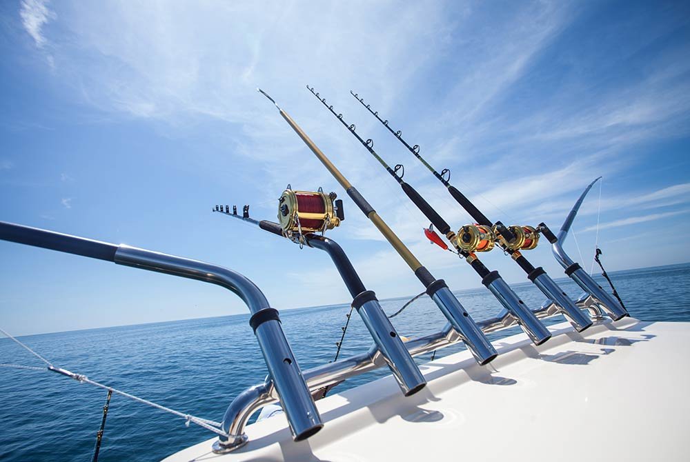 Five fishing rods held in rod holders on the back of a boat facing the open ocean under a clear blue sky, a classic among things to do in Port St. Joe, Florida.
