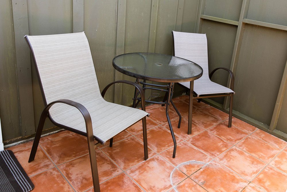 Two outdoor chairs and a small glass-topped table on the tiled patio of an oyster shell room at Cape San Blas Inn.