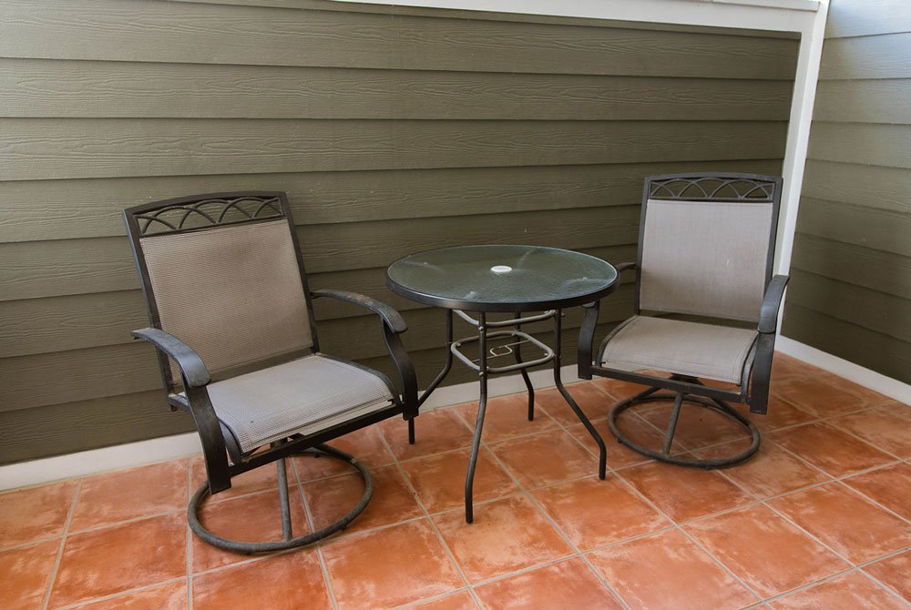 Two outdoor swivel chairs and a small glass-top table on the tiled patio of the Sand Dollar Room at Cape San Blas Inn.