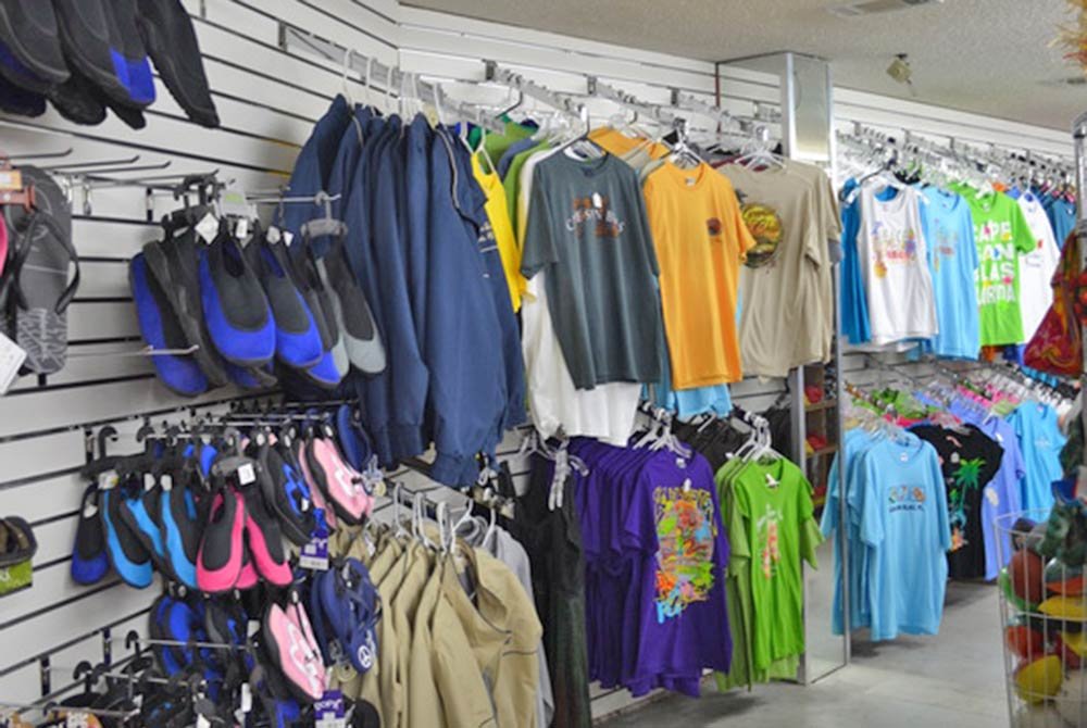 Store wall display of colorful t-shirts and assorted water shoes for things to do in Port St. Joe, Florida, hanging on racks.
